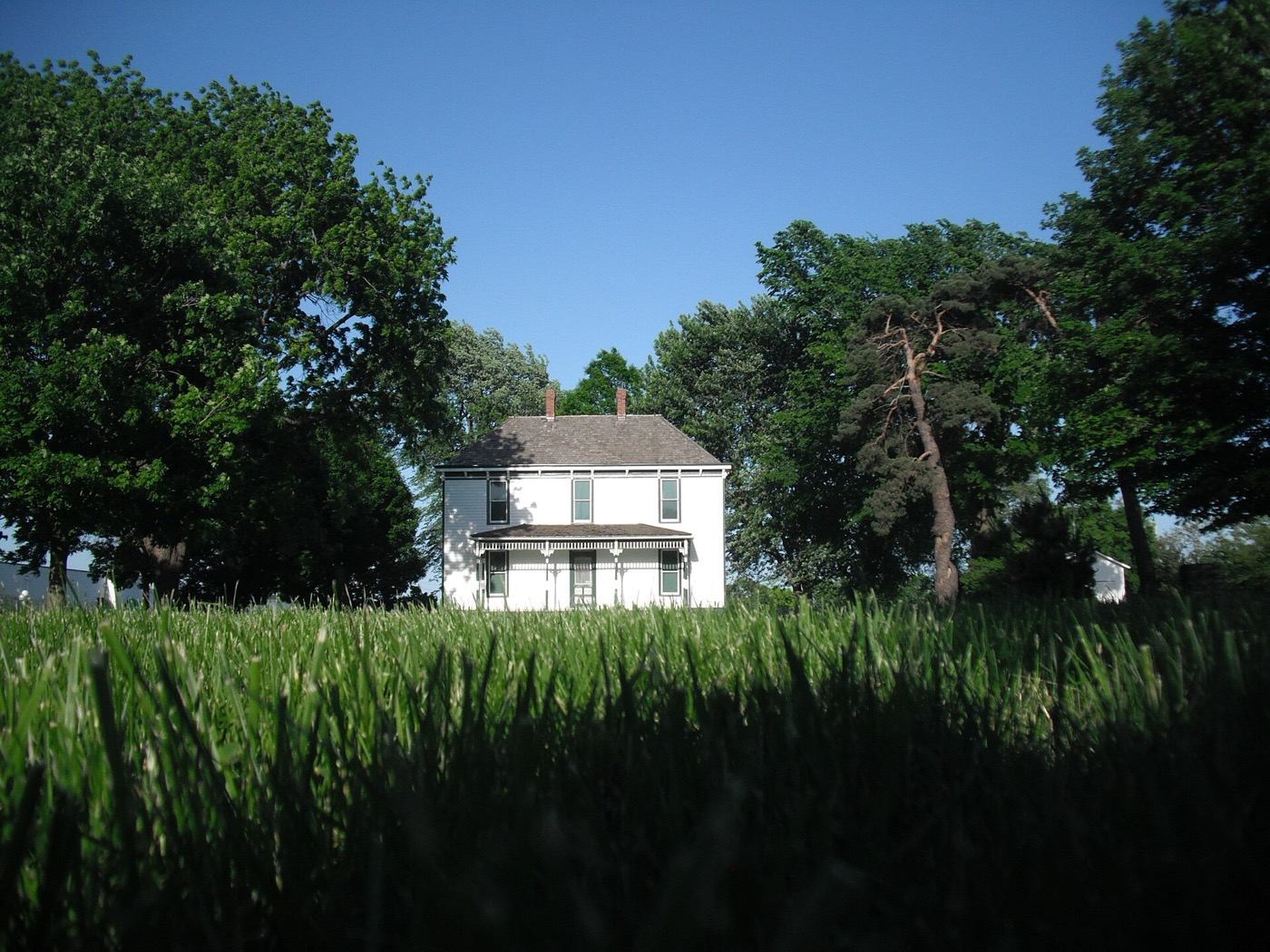 White two-story Truman Farm Home among trees at the Harry S Truman National Historic Site in Grandview, Missouri