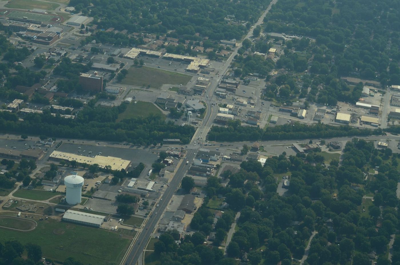 Aerial view of Raytown, Missouri, with a main road, commercial buildings, a water tower and wooded neighborhoods