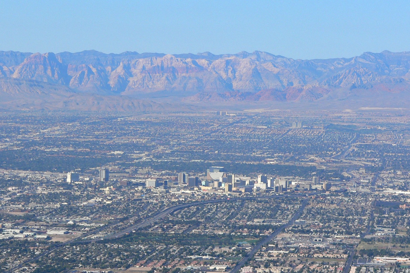 Downtown Las Vegas high-rises in the valley with Red Rock Canyon's mountains behind, seen from Frenchman Mountain