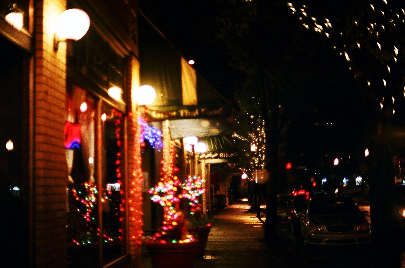 Storefronts on a downtown Gresham street decorated with holiday lights at night