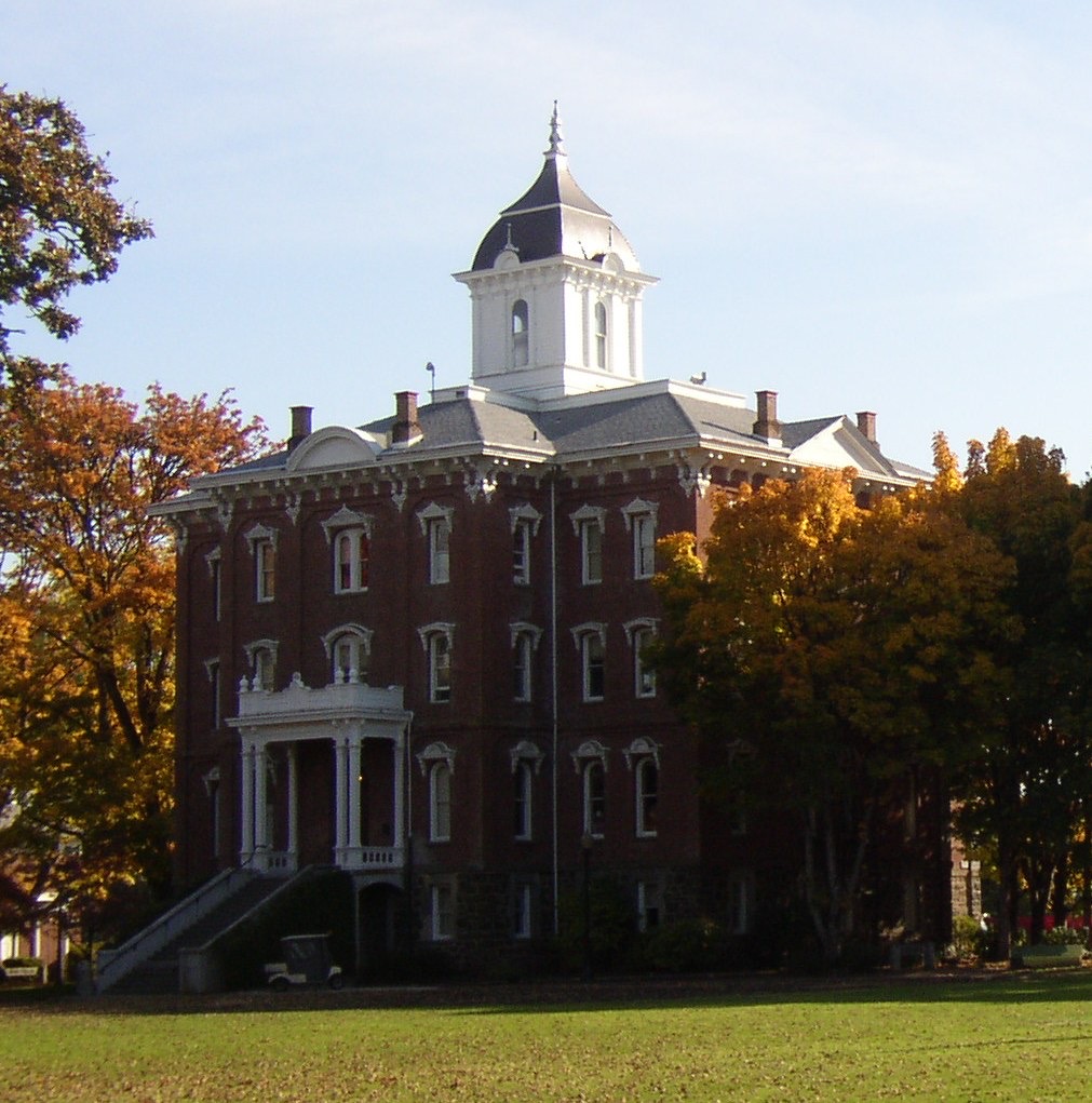 Historic brick Pioneer Hall with a cupola on the Linfield campus in McMinnville, framed by autumn trees