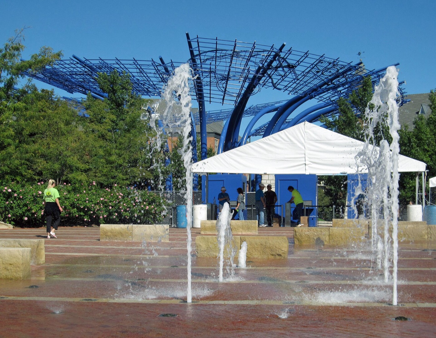Fountains spraying in the plaza at Addison Circle with a blue metal canopy sculpture