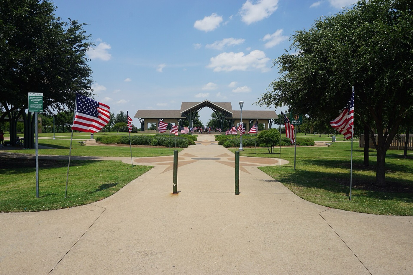 Walkway lined with American flags leading to a pavilion at Frisco Commons park in Frisco, Texas