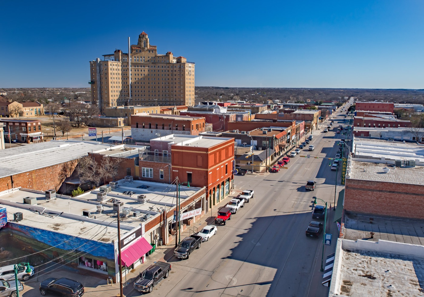 Elevated view down a downtown Mineral Wells street, with a tall historic hotel tower on the skyline