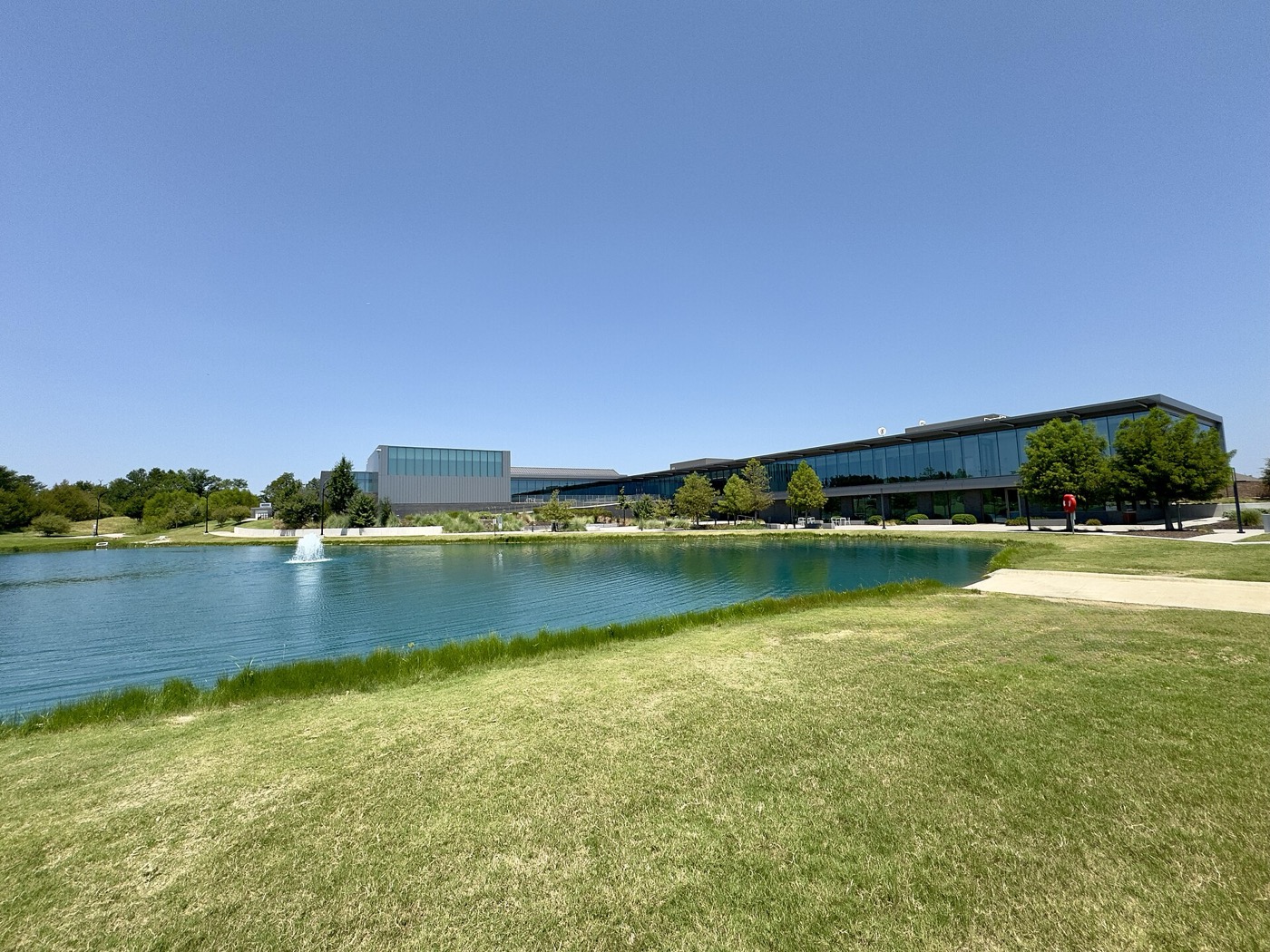 Modern glass Princeton Municipal Center seen across a pond with a fountain in Municipal Park