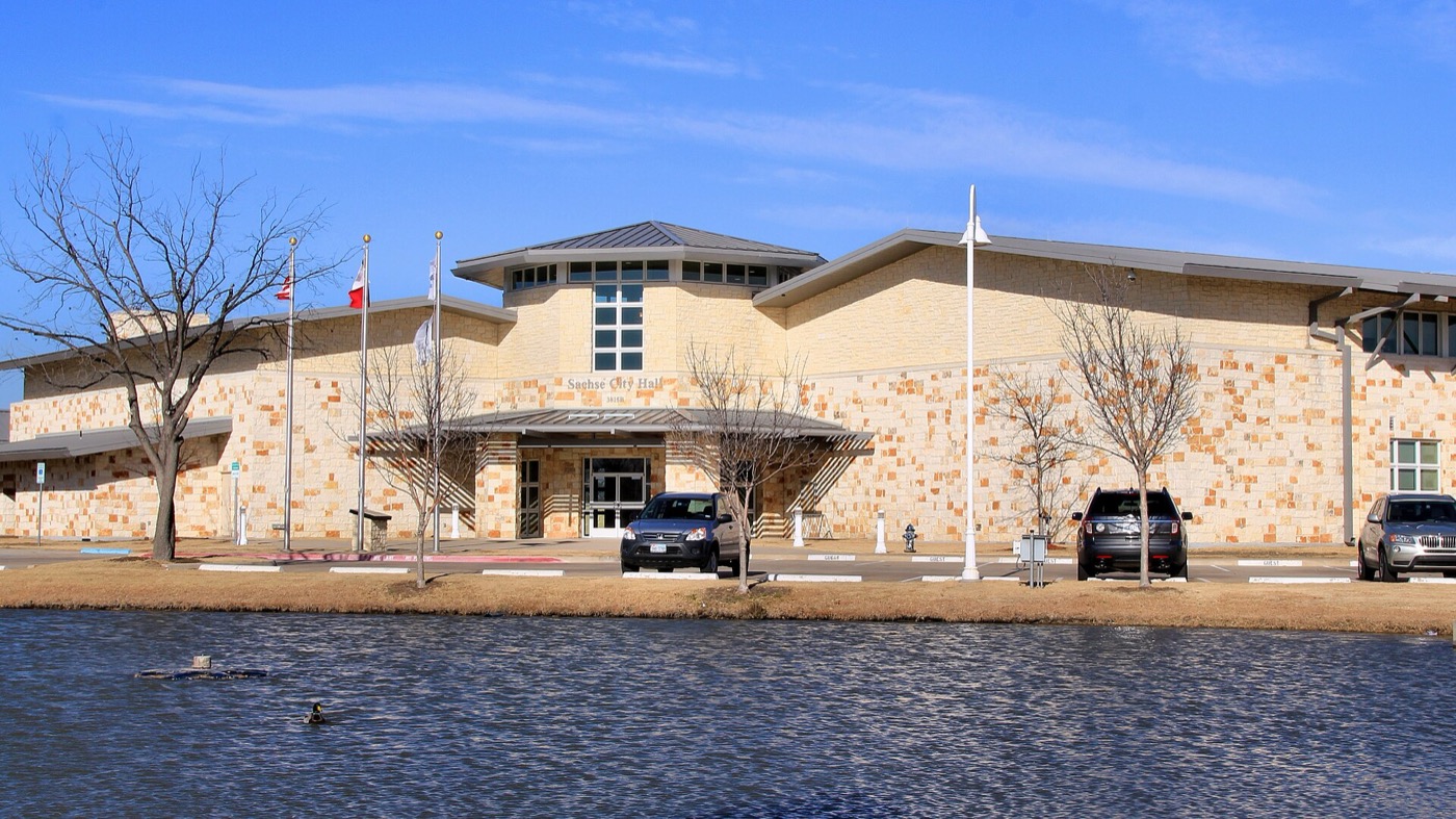 Sachse City Hall building with stone facade beside a pond