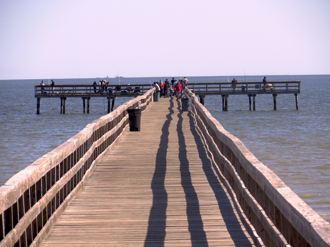 Long wooden fishing pier stretching into Galveston Bay at Pine Gully Park