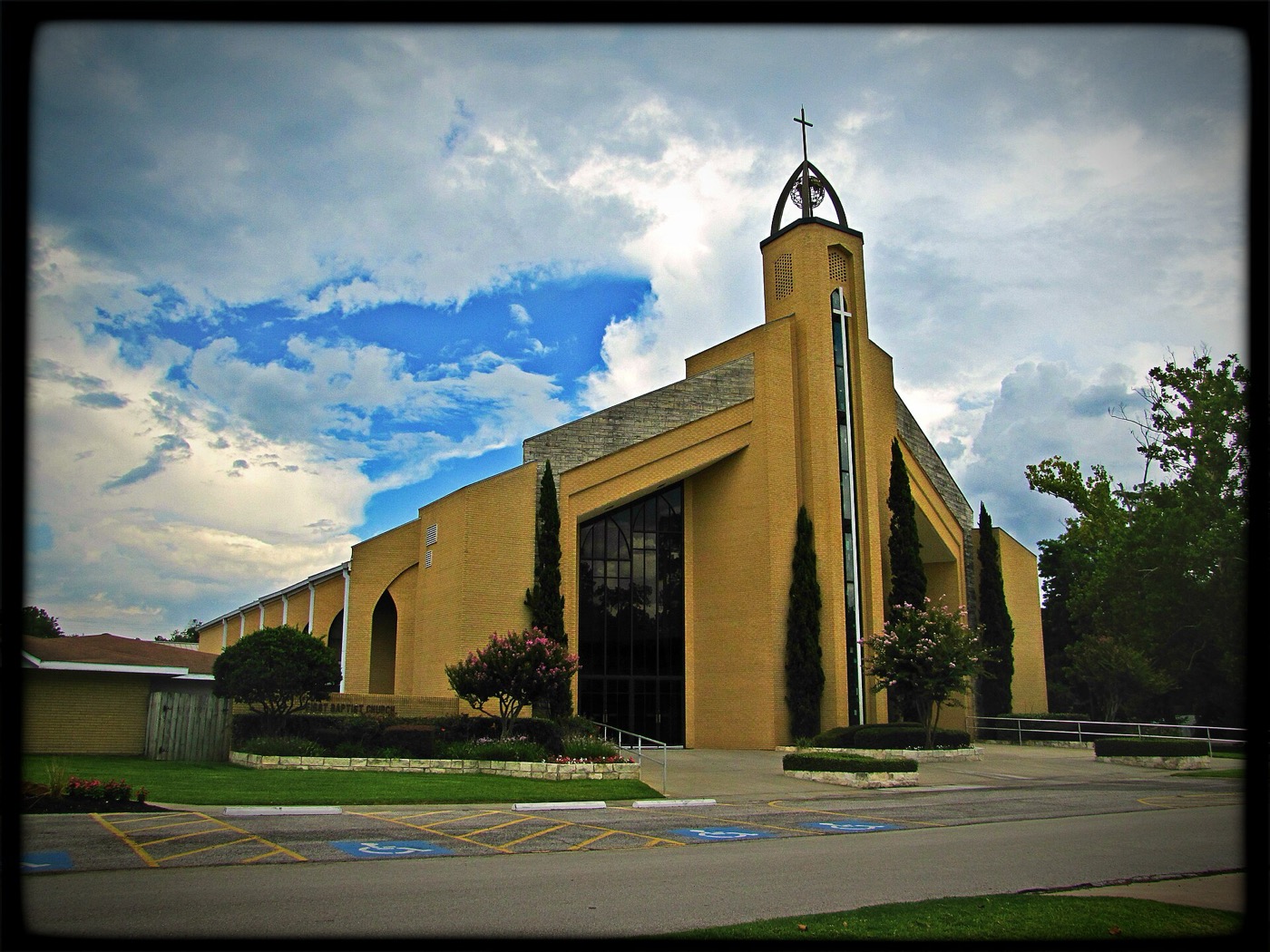 First Baptist Church building in Tomball, Texas, under a cloudy sky