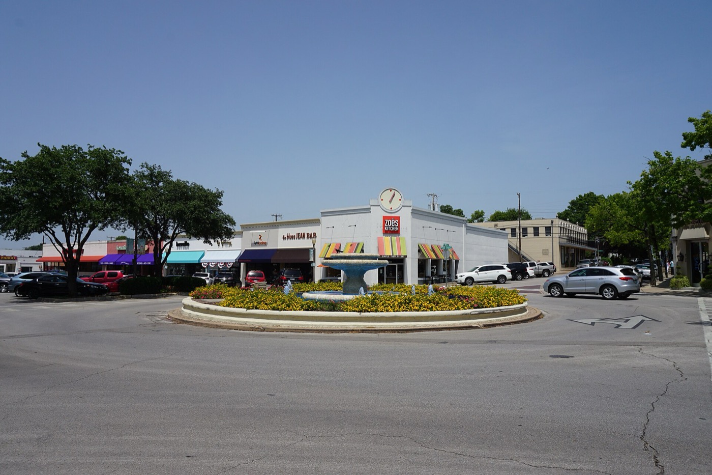Landscaped traffic circle and low-rise shops at Snider Plaza in University Park, Texas