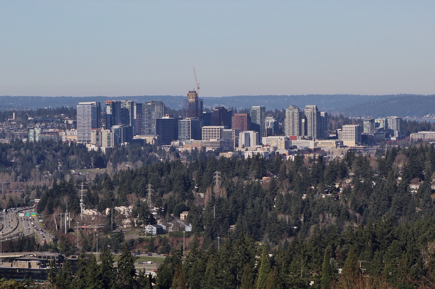 High-rise towers of downtown Bellevue rising above tree-covered hills