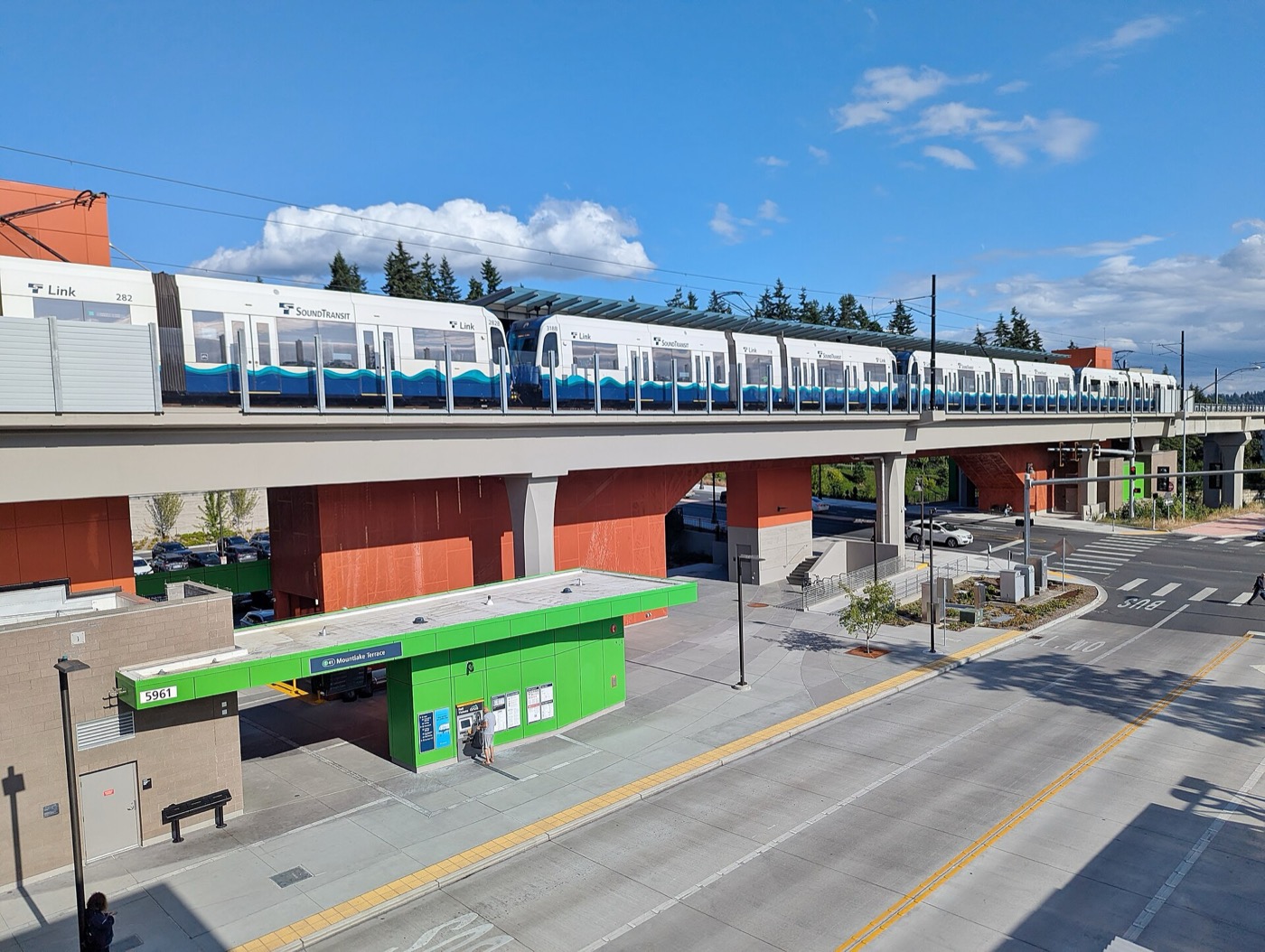 Elevated Link light rail train at Mountlake Terrace station with a transit plaza below