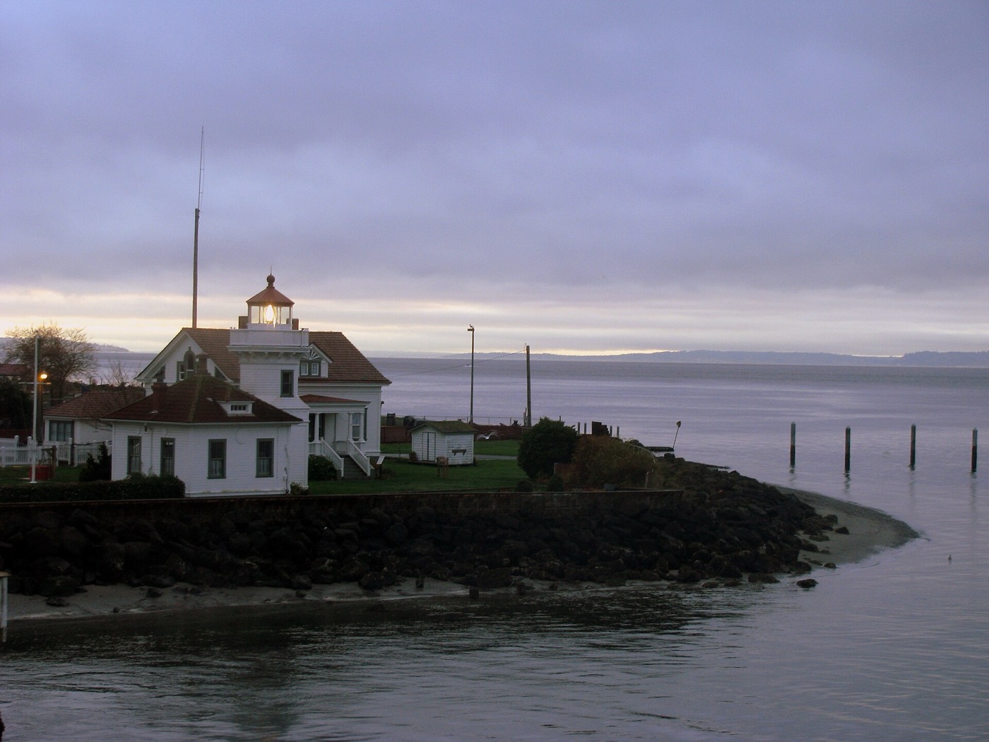 The white Mukilteo lighthouse and keeper's quarters on the shore of Possession Sound at dusk